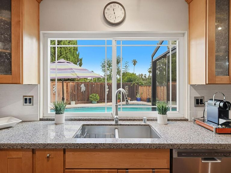 The remodeled kitchen at 4002 Agatha: quartz counters, stainless undermount sink, a wall of garden window framing the pool view