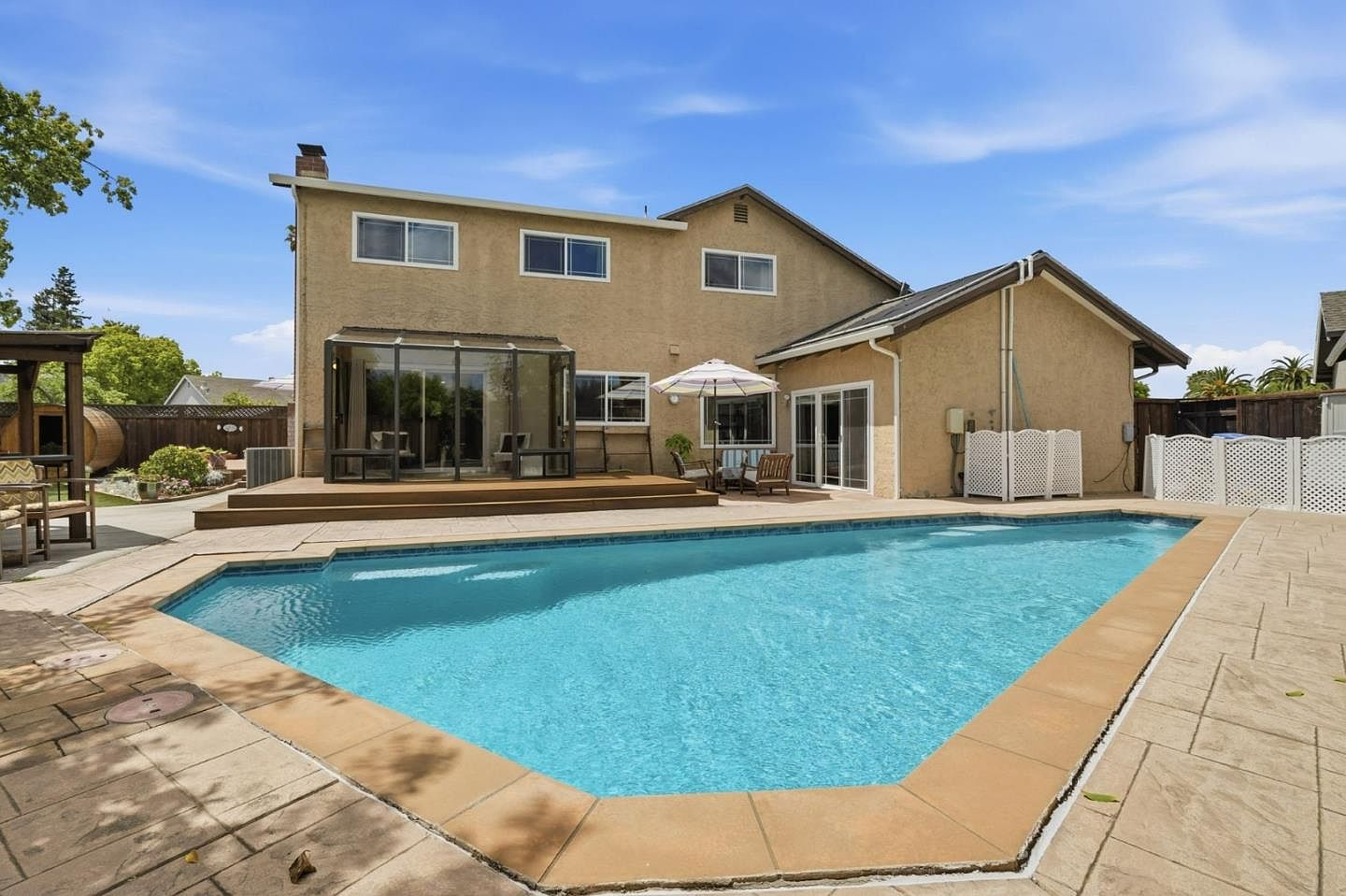 The rear elevation of 4002 Agatha Way, a two-story stucco residence overlooking an in-ground solar-heated pool, paver deck, and BBQ gazebo